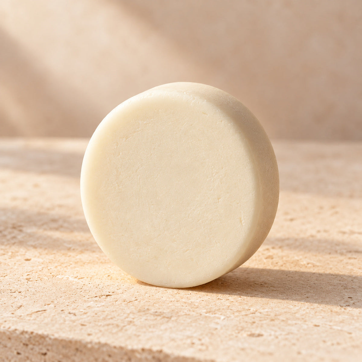 Acondicionador sólido Suavidad Extrema de maro naturals, barra redonda color marfil sobre piedra beige.